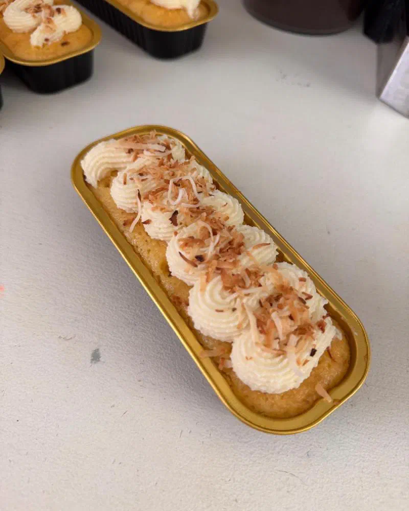 A pineapple coconut tin cake piped with frosting and toasted coconut