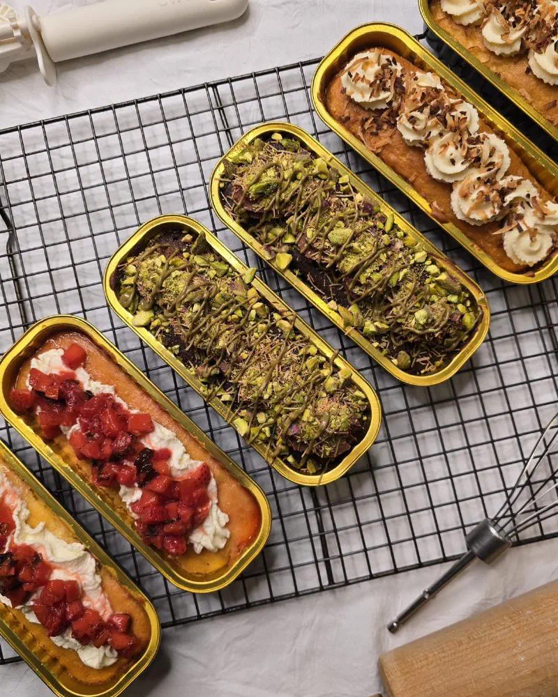 Strawberry, Dubai chocolate and coconut tin cakes on a cooling rack
